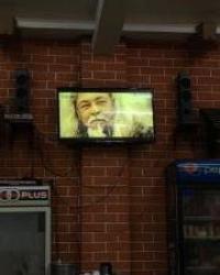 Man on television in front of brick wall